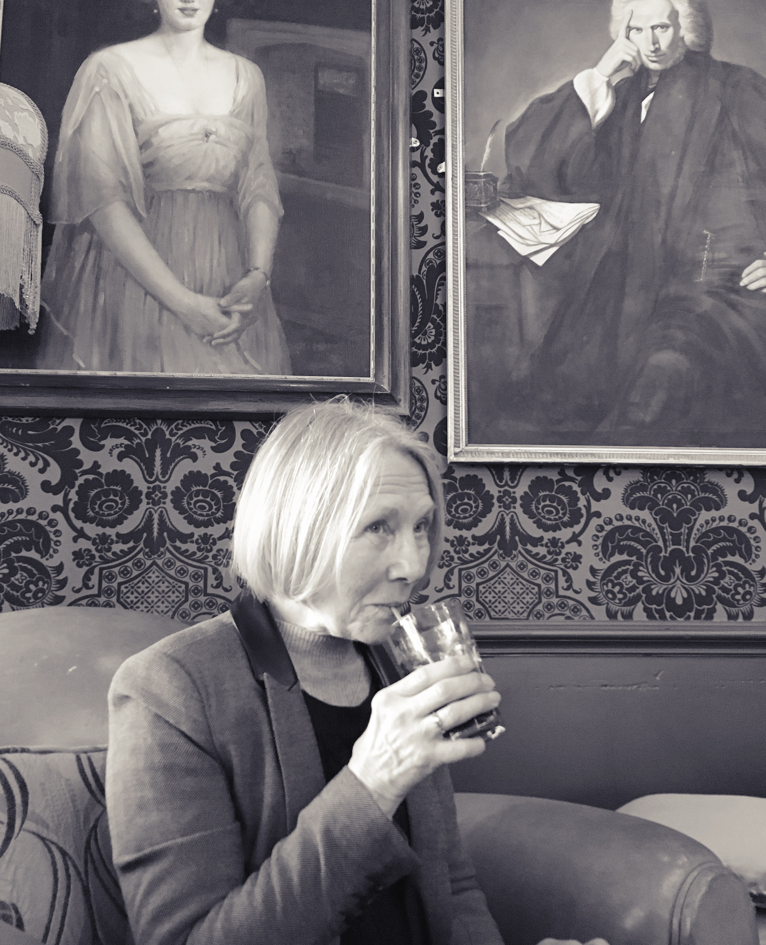 A photo of my mum taking a drink in a pub. It's in black and white.