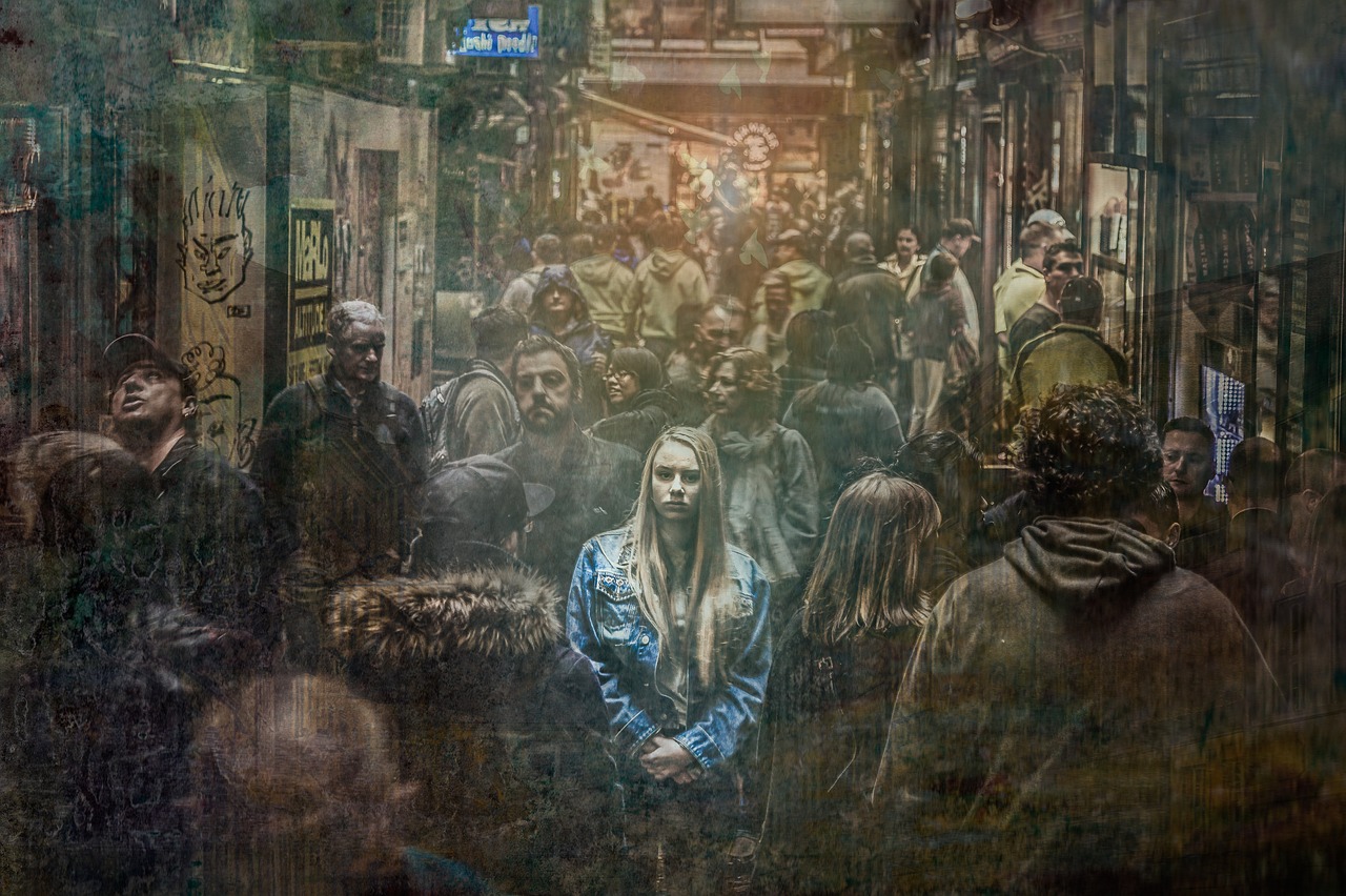 A dark digital image of a woman in an alley filled with people, while only she has a little light cast on her, looking up to the camera as though lonely in a sea of people.