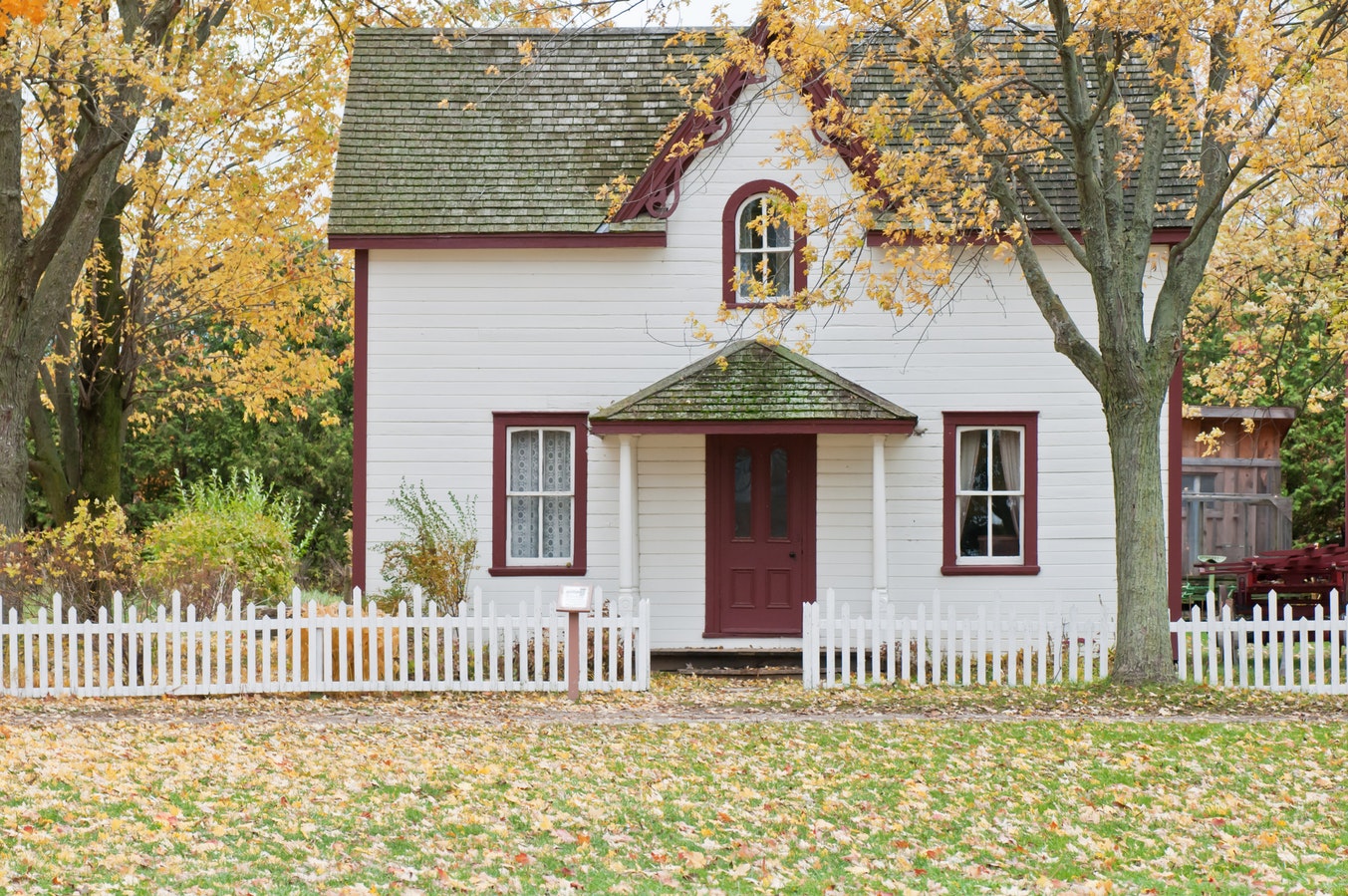 Photo of a house with a white picket fence and grass out front.