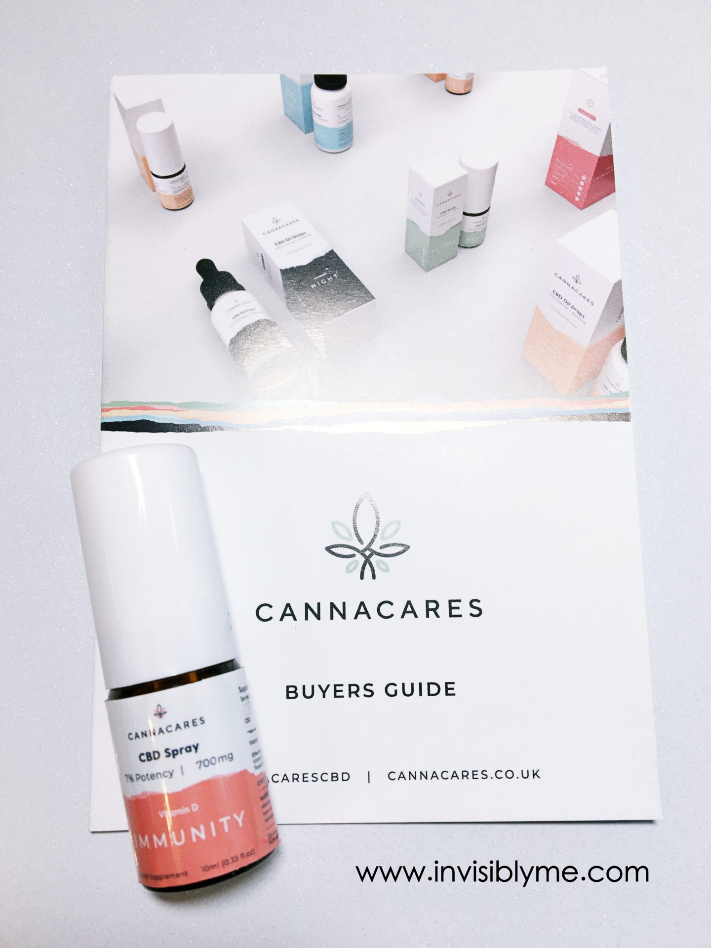 A bird's eye photo of the white and peach bottle of CBD Immunity spray from Cannacares for my review on top of the brochure.