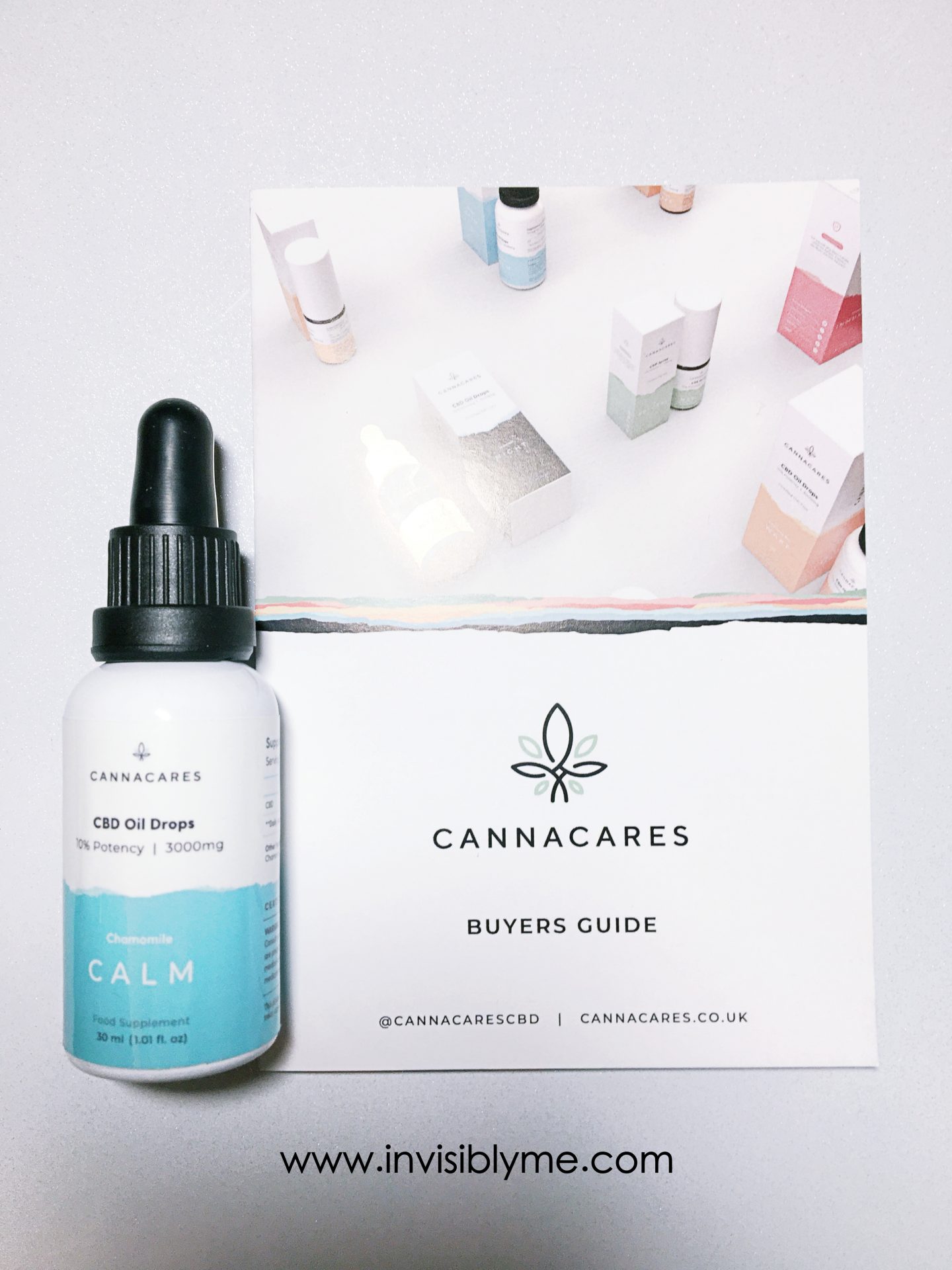 A bird's eye photo of the white and blue bottle of CALM oil drops from Cannacares for my review on top of the brochure.