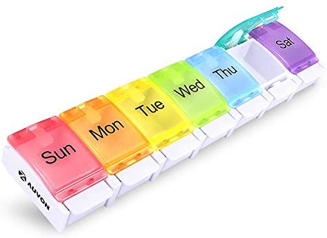 An Amazon stock image of the Auvon rainbow 7 day pill box. It's a long rectangular plastic box, essentially with Sunday through to Monday as separate compartments, each with a different coloured lid. There are three letters for each day written on top of the lids in black. At the front of each lid is a lip, which you press down to pop up the lid.
