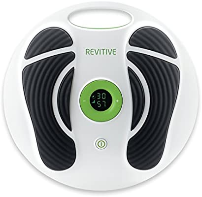 A stock photo of the Revitive Circulation Boost against a white background. It's a white circular device, with green detailing in the centre and on the back. There are two large black 'footprints' on the device where you put your feet, with white spaces to separate the parts of the feet receiving the current. In the middle is a digital screen.