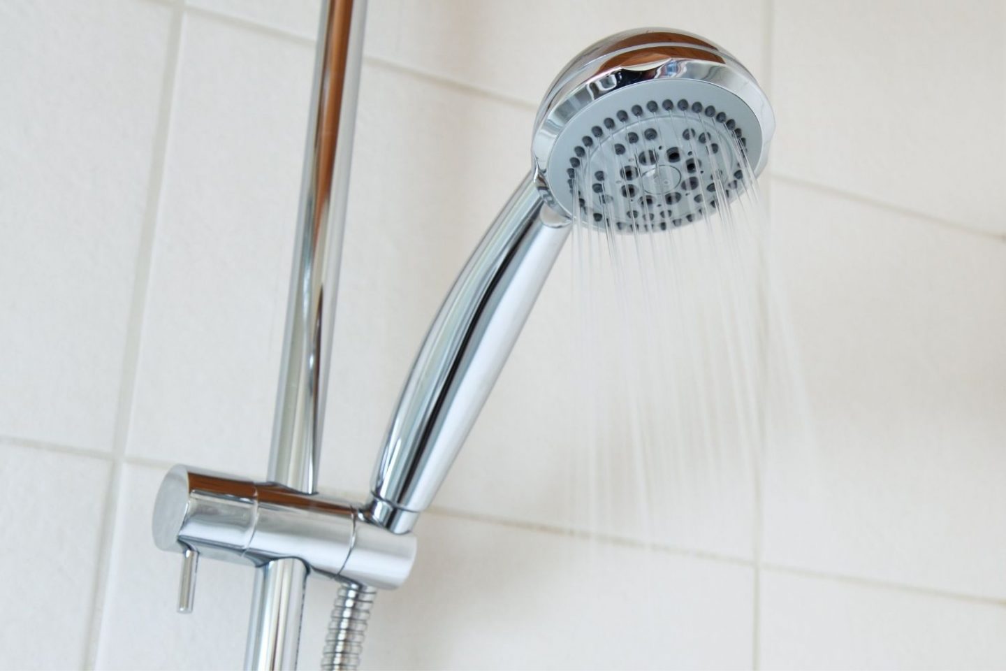 A photo of a shower, showing just the top part with the chrome shower head as it sprays water.