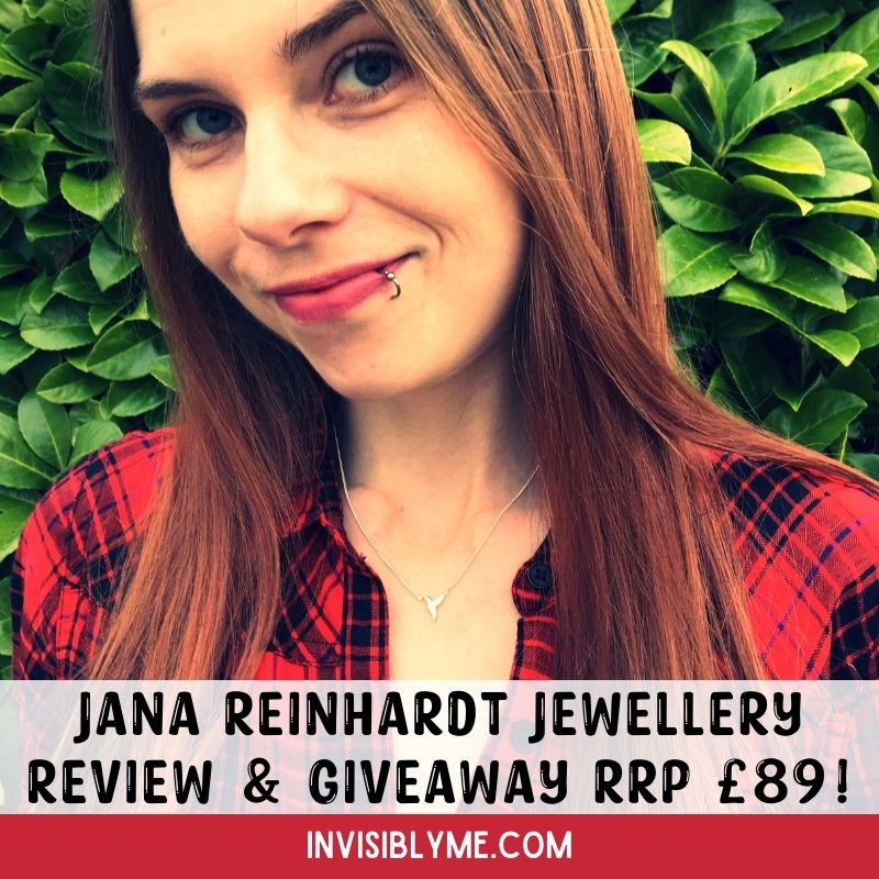 A photo of me with my head tilted to the right slightly wearing the Jana Reinhardt hummingbird necklace I was gifted for review. I have long brown hair and I'm wearing a red and black check shirt. Behind me are the lush green leaves of a plant in my garden. The photo has been darkened for effect. Underneath is the post title: Jana Reinhardt Jewellery Review and giveaway worth £89.