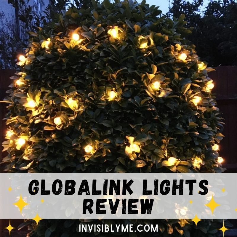 A photo taken of the large green leaf bush in the garden in the evening. It's still somewhat light outside. The GlobaLink lights have been strung around the plant and lit up. Underneath is the title, along with some yellow star-shapes for decoration: GlobaLink Lights Review.
