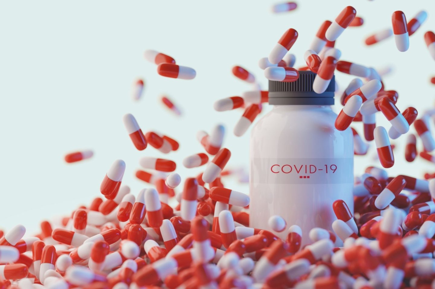 A white pill bottle with hundreds of red and white capsules falling from above all around it to suggest Covid19 treatments.